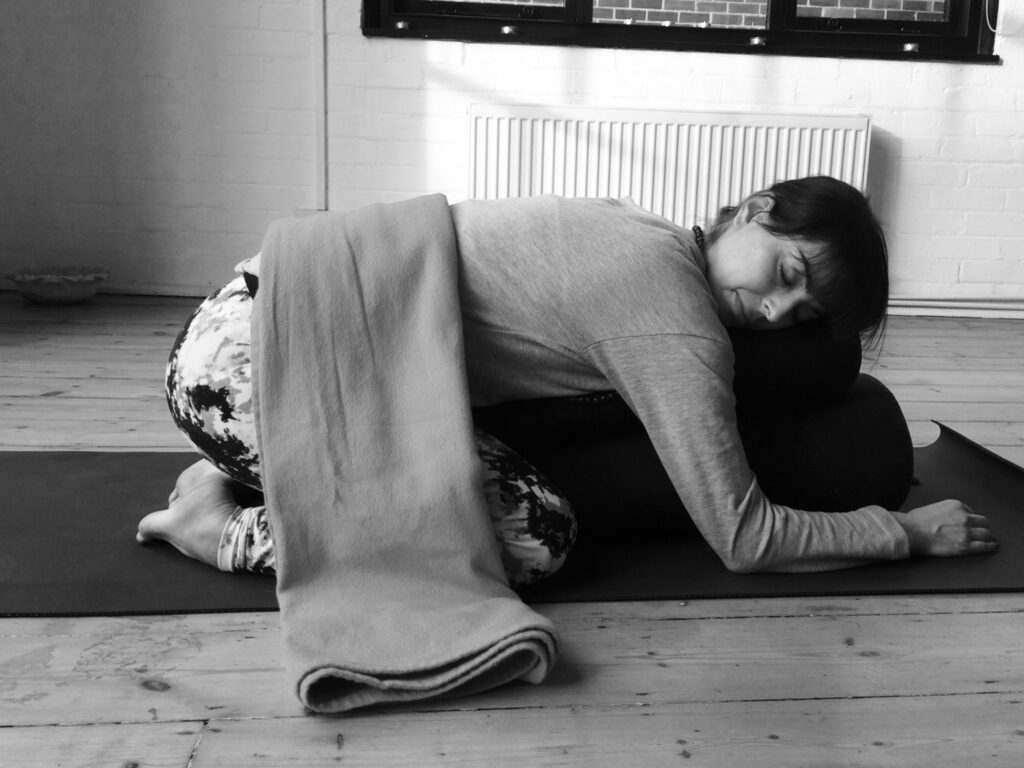 New Flow and Restore Class at PYC 5 Black and white photo of a teacher supporting a student in a deep forward fold