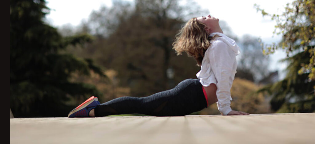 A woman in cobra pose on a path outdoors