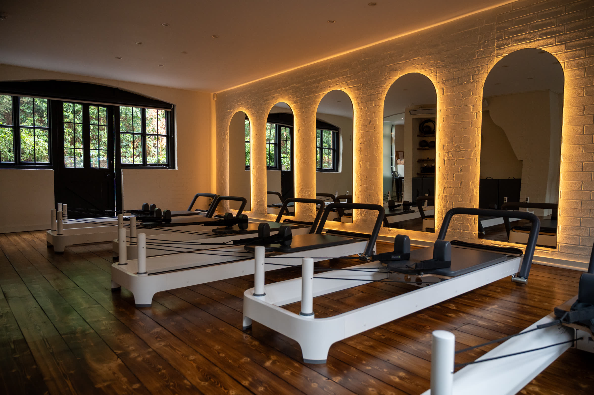 Reformer studio with a row of reformers, windows and lit arches