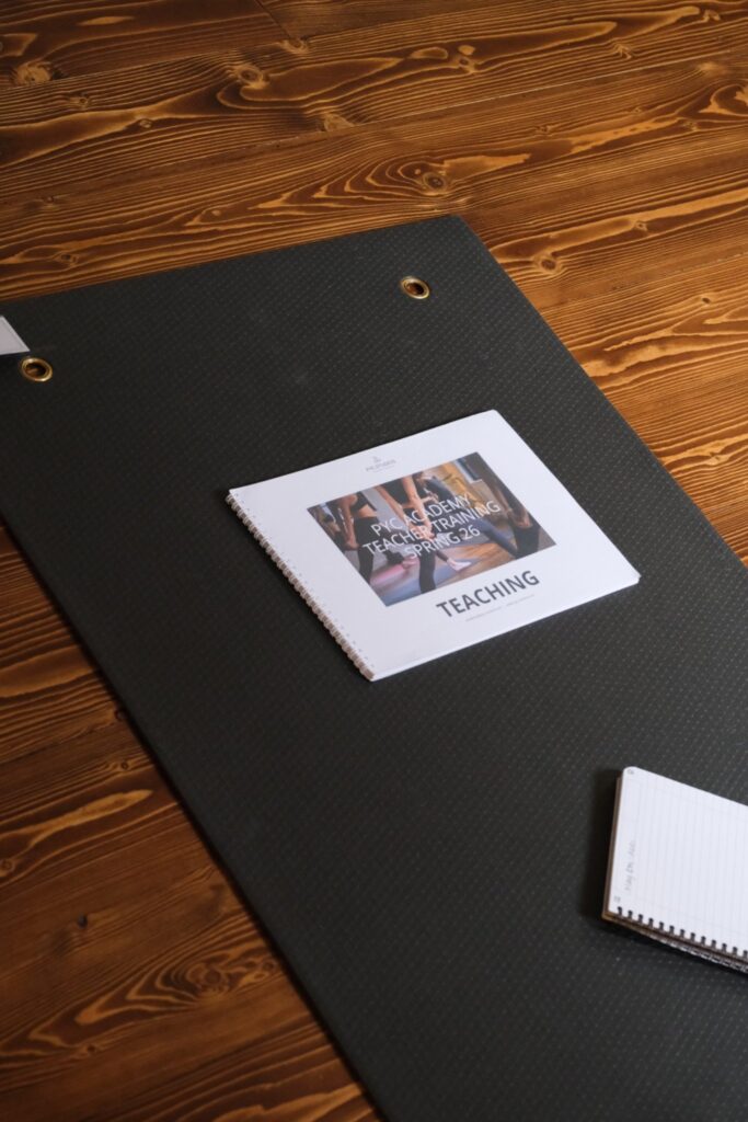 Teacher training manual and notebook on a yoga mat at PYC Studios